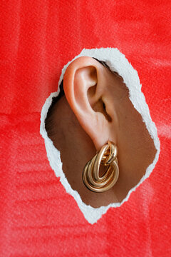 Gold earring in the ear on a red background