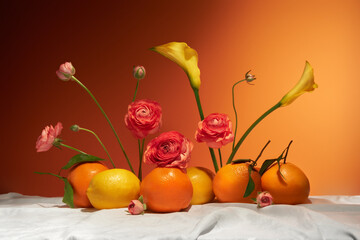 Still life with citrus fruits and flowers on white tablecloth