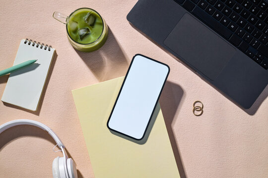 Overhead view of a workspace featuring a laptop and blank screen phone