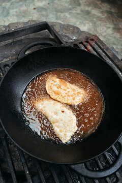 Frying Traditional Snacks in Rustic Kitchen
