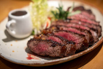Medium rare wagyu meat served on plate with sauce and vegetable