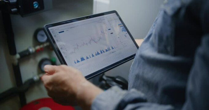 Employee Checking Real-Time Stocks and Exchange Market Charts Using Digital Tablet Computer. Man Making Investments During Working Hours in Workshop, Combining Job with Online Trading. Close Up Shot.