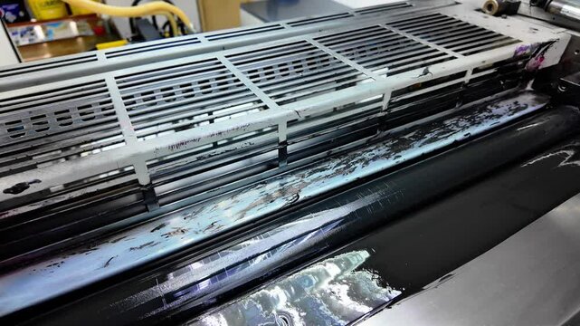 Close examination of the lithographic printing process showcasing the application of printing ink on the press. The machinery operates efficiently, vital for quality print production.