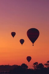 Four hot air balloons are flying in the sky at sunset