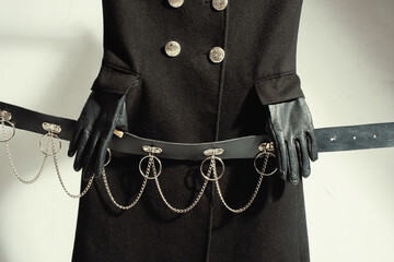 Black gothic coat with leather gloves holding chain belt