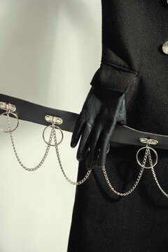 Black gothic coat with leather gloves holding chain belt