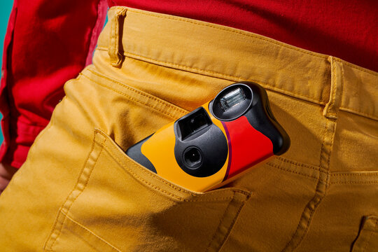 has a disposable camera in the back pocket of his pants