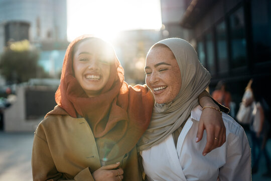 Two happy muslim businesswomen walking together on a city street