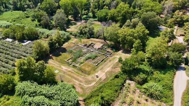 A panoramic view of ancient Greek ruins of Dion surrounded by agricultural landscape with mountains