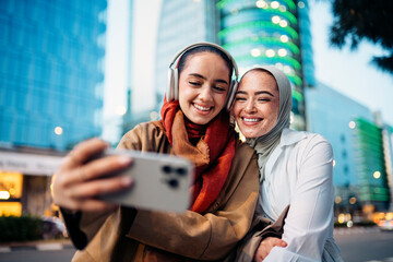 Two happy young women taking a selfie in a modern city