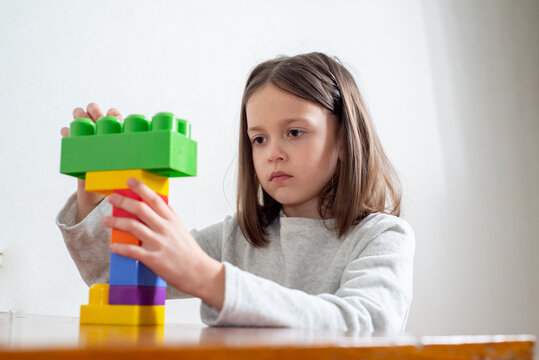 Child with autism without eye contact builds a tower of toy blocks