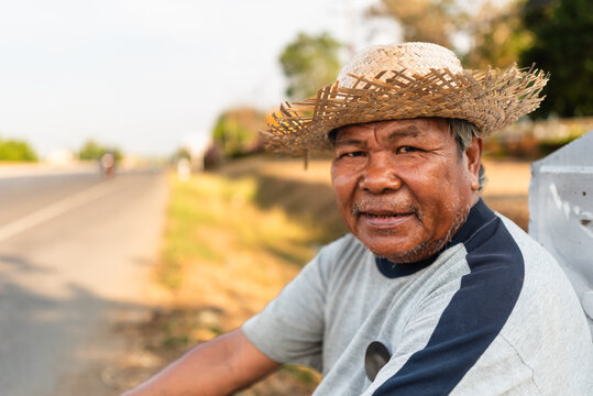 Elderly Thai man resting roadside with collected plastic bottles