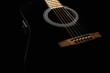 black electro-acoustic guitar on a black background, silhouette, close-up