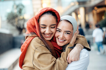 Two happy young muslim women hugging in the city