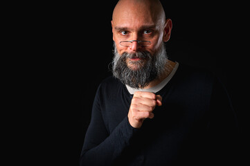 Funny bearded man with mischievous expression and clasped hands. Bald adult male posing on black...