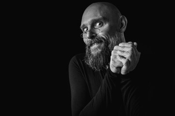 Black and white portrait of bearded man making silence gesture with finger on...