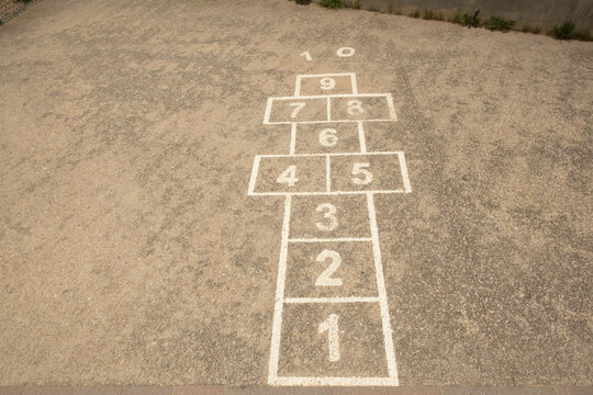 Hopscotch painted on worn light gray concrete ground