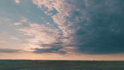 Obraz premium A Dramatic and Stunning Sky Over Expansive Open Fields During a Beautiful Sunset Time lapse.