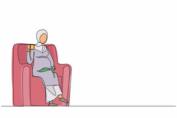 Single continuous line drawing pregnant Arabian woman sitting on sofa, reading book and drinking tea. Cozy evening with hot drink. Outside the winter. One line draw graphic design vector illustration