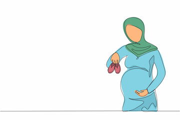 Single one line drawing small shoes for unborn baby in belly of pregnant woman. Arabian pregnant woman holding small baby shoes relaxing at home in bedroom. Continuous line draw design graphic vector