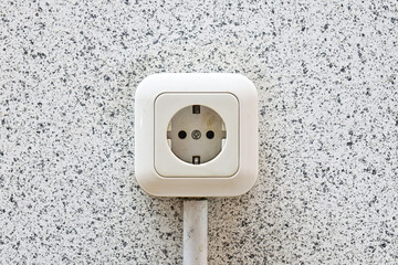 A white electrical outlet are mounted on a grey or gray wall. Concept of energy deficit and...