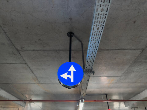 Blue Traffic Sign with Left and Forward Arrow in Parking Lot