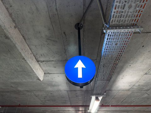 Blue Arrow Traffic Sign in Industrial Parking Garage Ceiling