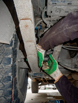Worker Repairing Leaf Spring and Shock Absorber Outdoors