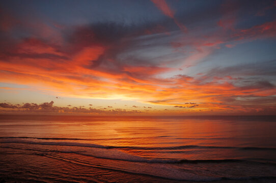 Tropical sunset over ocean with vivid orange and red clouds in Bali