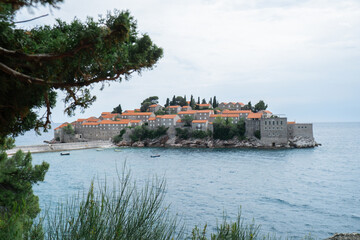 Naklejka premium Sveti Stefan private island in Montenegro near Budva. Adriatic Sea Coast travel destination vacation holiday idea. Concept of getting away tourism experiences. Nature driven scenery wanderlust vibes