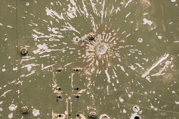 Impact marks and damage on a green metal surface from explosions