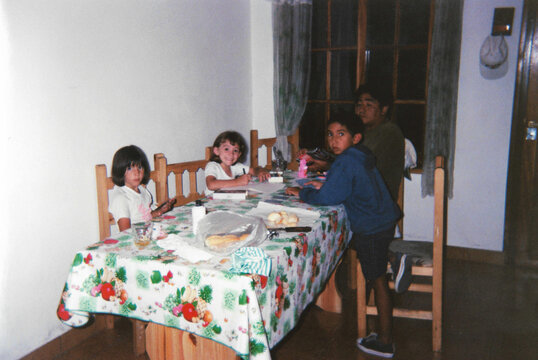 Cousins and uncle drawing together at the dining table during summer 