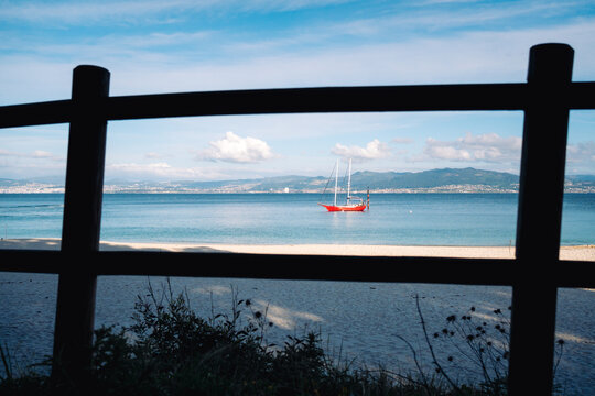 Red sailboat seen through wooden fence