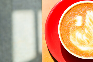 Extreme Close up view of hot cafe latte in the red cup. Wooden table, grey or gray floor, corner. Copy space. Coffee. Latte art. Top, above, high angle, Half. Dark, shadows, Black.