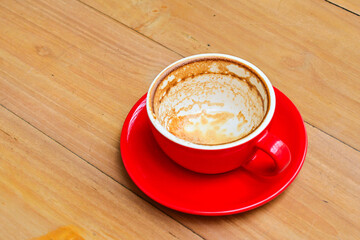 Close up view of empty red cup. Wooden table as the background. Copy space. After drink a coffee. Coffee shop.