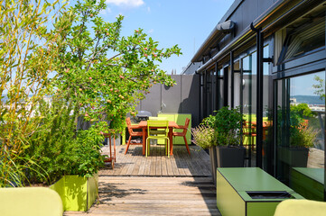Green and terracotta all-season weatherproof furniture for outdoor use on a rooftop terrace with an apple tree in front