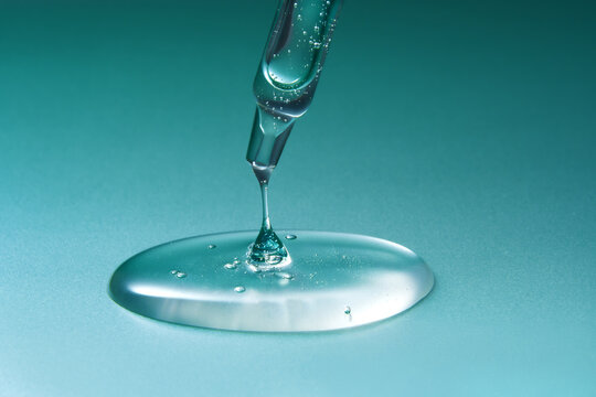 Glass pipette with anti-age moisturizing face serum on blue background
