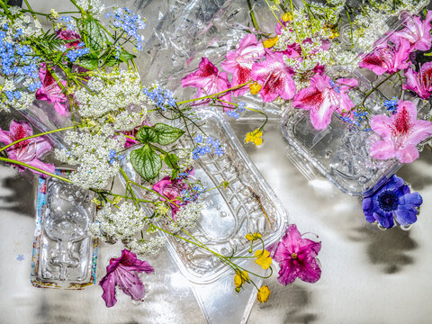 Flowers with plastic waste, packaging floating in water.