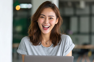 Cheerful young Asian woman with medium brown hair wearing casual gray t shirt smiling happily indoors