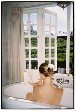Woman Relaxing in Bathtub Reading a Book
