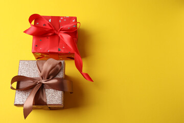 Gift box with a bow on a yellow background, top view. Space for text