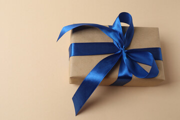 Gift box with a bow on a beige background, top view. Space for text