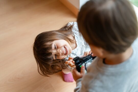 Naklejki Little girl laughing while boy is taking pictures with vintage camera