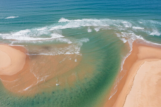 Shallow coastal river flowing out to sea between beaches