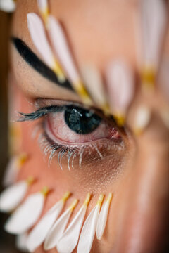 Extreme close-up of eye framed by petal decoration and painted lashes