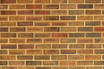 Abstract texture background of an exterior multi-shade reddish brown vintage brick wall surface speckled with blue, in traditional running bond brickwork pattern