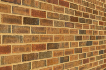 Abstract texture background of an exterior multi-shade reddish brown vintage brick wall surface speckled with blue, in traditional running bond brickwork pattern