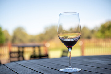 Obraz premium A glass of red wine on the table, with blur background of the vineyard