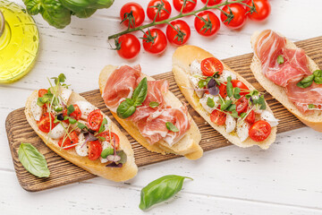 Tasty antipasto toasts featuring classic caprese with mozzarella and tomatoes, and savory prosciutto with herbs