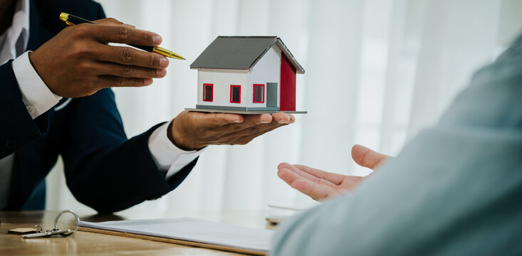 Two people exchanging house keys and signing documents, symbolizing home buying, mortgage, investment, and financial planning in real estate.